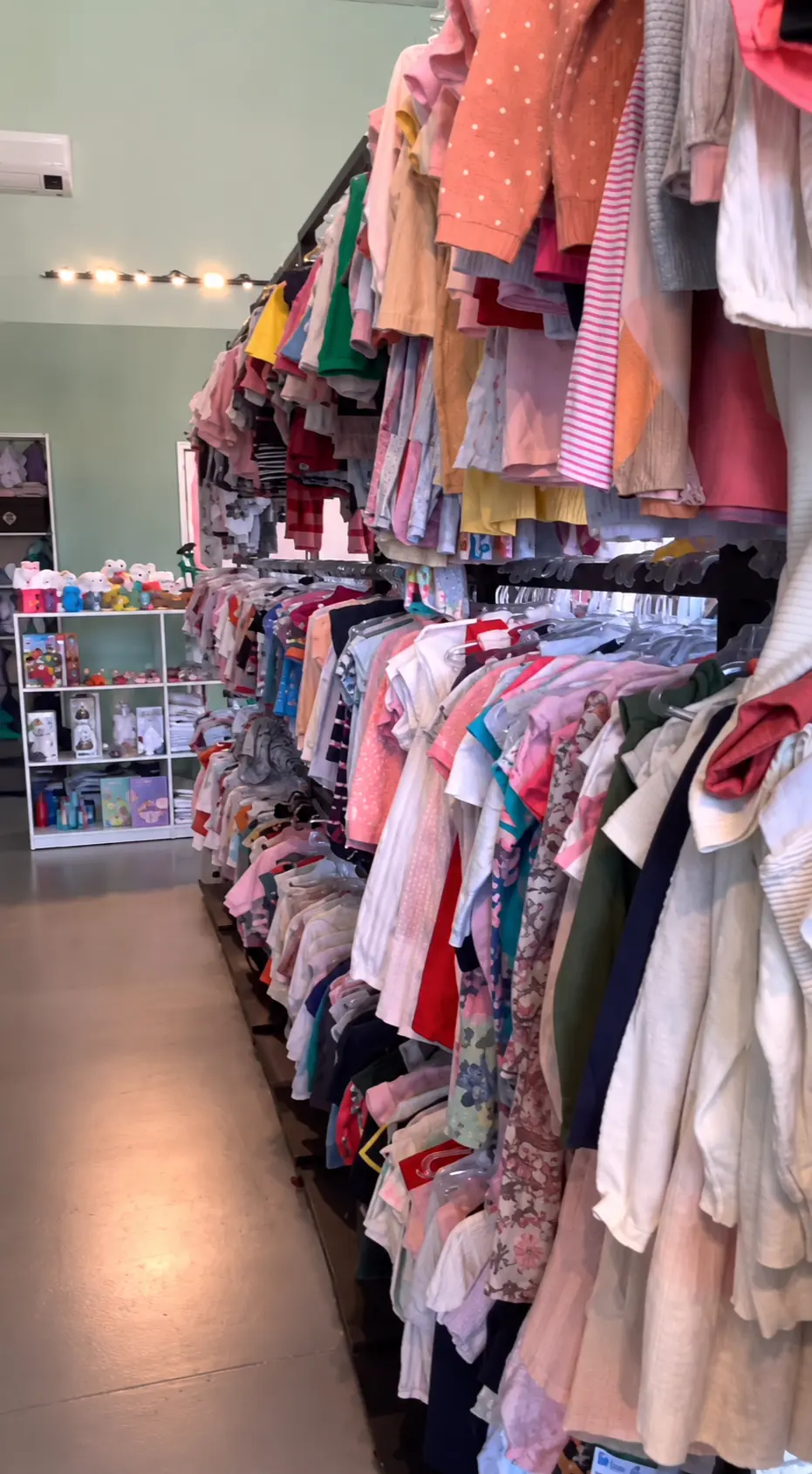 Interior da loja Paula's Kids com araras de roupas infantis